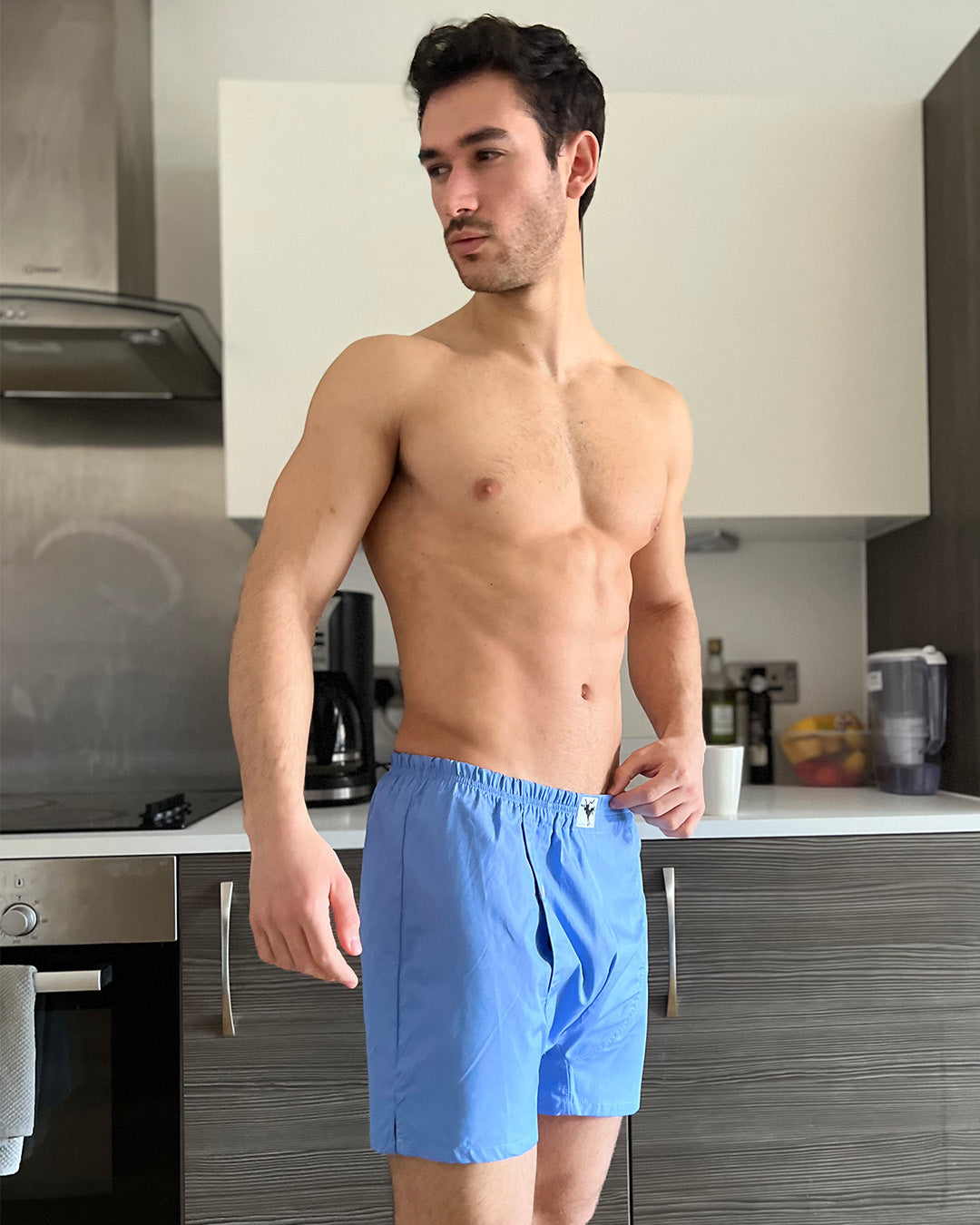 Man wearing blue boxer shorts in a kitchen