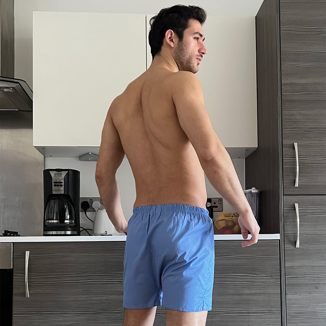 Man wearing blue boxer shorts in a kitchen setting